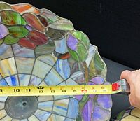 Close-up of floral stained glass lamp shade with tape measure showing about 16 inches diameter