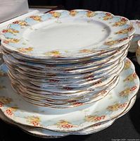 Stacked dessert plates showing floral pattern with yellow and red roses on a pastel blue band with gold trim.