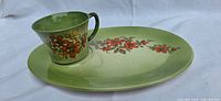 Tea cup placed on matching luncheon plate showing the green glaze and floral design.