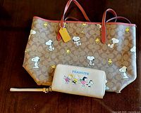 Tote bag and zip wallet displayed side by side on wooden table