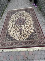 Full rectangular traditional Ankara area rug spread out on brick pavement showing overall design and coloration.