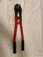 Full view of red bolt cutters against a fabric background