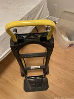 Front view of black and yellow Harper foldable dolly with handle and foldable base platform