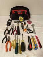 Photo shows front view of the Jobmate tool bag and all tools laid out, including tape measure, hammer, pliers, screwdrivers, scissors, adjustable wrench, cutting knives, tweezers, and small red component container.