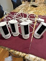 Front view of four white Ring Stick Up Cam Wired cameras standing upright with attached cables on tabletop.