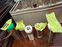 Five clear tubes containing U.S. wheat pennies sorted by year, each tube labeled with year and origin noted as USA coins.