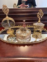 All items arranged on oval mirrored tray in front of dresser mirror