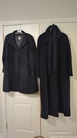 Pair of two women's winter coats hanging on a door, showing full length and style