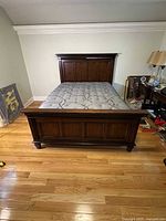 Full view of queen size traditional dark brown wooden bedframe with mattress on top