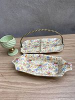 Full view of two Royal Winton Floral Feast chintzware dishes and one green Hull USA goblet with gold trim on a wood surface.