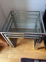 Two metal-frame nesting tables together, one nested under the other