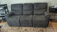 Front view of three-seat dark grey microsuede power reclining sofa with plush backrests.