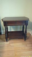 Single side table showing overall design, mahogany wood finish, turned legs, drawer, and shelf.