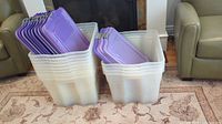 Front view of 13 translucent stackable totes with purple lids stacked in two columns