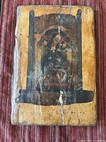 Front view of wooden religious icon artwork showing central religious figure and visible wear and cracks.