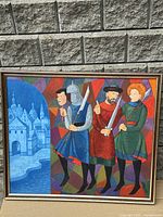 Front view of framed colorful wooden artwork showing three medieval figures with swords and a castle in background.