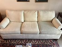 Front view of beige 3 seat couch with three cushions, showing overall condition and fabric texture.