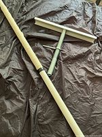 Photo of foam-wrapped adjustable safety pole and detachable T-shaped metal squeegee head on black fabric.