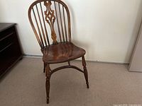 Full view of one antique wooden chair showing curved back, contoured seat, turned legs