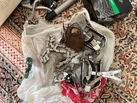 Overview of assorted bike parts with chains, pedals and other metal bike components on a patterned rug.