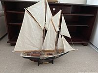Full view of Bluenose model showing wooden hull, cloth sails, rigging, and display stand