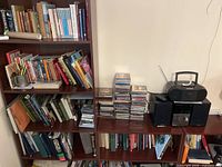 Large wooden bookshelf wall unit with multiple shelves arranged with books, CDs (not included), and audio players (not included).