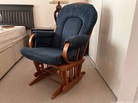 Front angled view showing blue fabric upholstered cushioned rocking chair with pine wood frame.