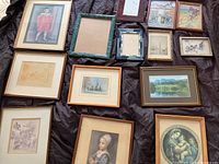 Top view of assorted framed pictures showing a variety of portraits, landscapes, and sketches mostly smaller sizes.