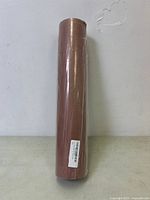 Single roll of brown butcher paper, sealed in plastic, viewed standing upright with label sticker visible