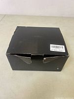 Closed black box with a sticker label stating Made in China, slightly damaged corner.