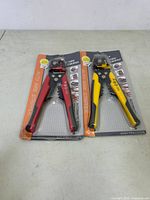Two automatic wire stripper and crimper tools, one with red handles and one with yellow handles, in sealed plastic and cardboard packaging.