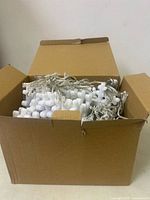 Open cardboard box showing bundled white snowflake string lights packed inside.