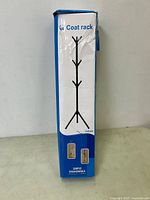 Photo of the front side of the coat rack box showing image of the rack, product code YX9104, and label 'Coat rack'. The box is slightly damaged but contents appear unopened.