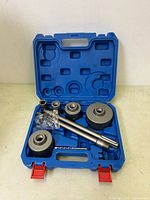 Opened blue plastic carrying case showing multiple hole saw cutters, drill bit, extension rods, and small metal connectors for concrete drilling