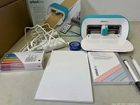 Overview of Cricut Joy machine, power adapter, pen set, cutting mat, cutaway cards, tools, transfer tape and original box
