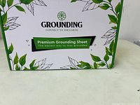 Close up of the box front with branding Grounding and Premium Grounding Sheet text showing the product is a grounding sheet to connect to earth.