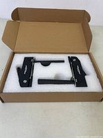 Photo of two new black aluminum hold down clamps in original box with foam insert for protection