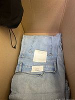 Folded light wash denim jeans with Everlane tags inside a box