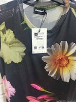 Close-up of black mesh Desigual top with yellow and white floral print and size small tag