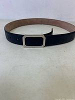 Front view of navy blue leather Gucci belt showing embossed pattern and rectangular silver buckle.