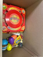 Box with a red spinning battle game base and colorful egg-shaped toys