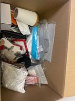 Photo showing a mix of miscellaneous items including packaged household goods, pet collar, and small boxed items in a box