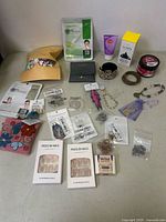Single photo showing entire assortment of necklace, earrings, jewelry pieces, skincare tubes, and pouches on a table.