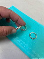 Hand holding two Pandora rings including the one with round silver beads and the stone embedded narrow band ring, placed on blue bubble wrap background.