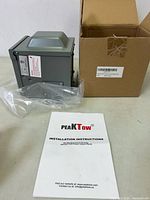 Photo of unopened Peak Tow 125/250 Volt 50 Amp power outlet panel with packaging and installation instructions booklet.