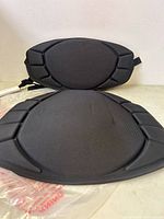 Two black Pelican brand water repellent boat seat cushions shown stacked, with contoured shape and padded edges.