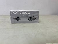 Side view of the intact unopened box showing 'Pop Race' branding and side profile illustration of the silver Singer Targa model car.