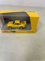 Yellow Porsche 911 RSR model in clear display box with yellow base and branding.