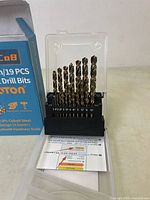 Front view of the drill bit set showing the bits arranged by size along with partial packaging and an information card below.