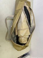 Tan carrying bag partially unzipped revealing the folded tent fabric inside.